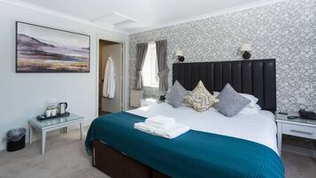 Un dormitorio ordenado con cama, mesitas de noche, una lámpara y un cuadro en la pared.