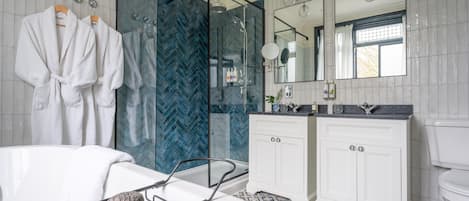 A modern bathroom with a bathtub, two sinks, a shower enclosure, and a large mirror.