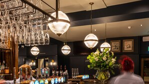 A bar area with a wooden counter, multiple beer taps, and hanging light fixtures. - The Crown Inn (Chislehurst)