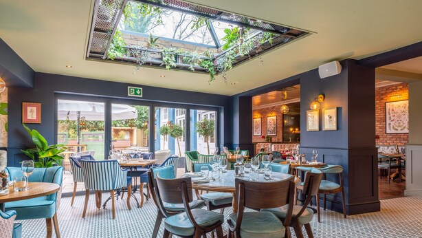 A restaurant with a checkered floor, blue and striped chairs, and a ceiling garden. - The Crown Inn (Chislehurst)