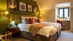 A neatly arranged bedroom with a bed, bedside tables, a chair, and artwork on the wall. - The Crown Inn (Chislehurst)