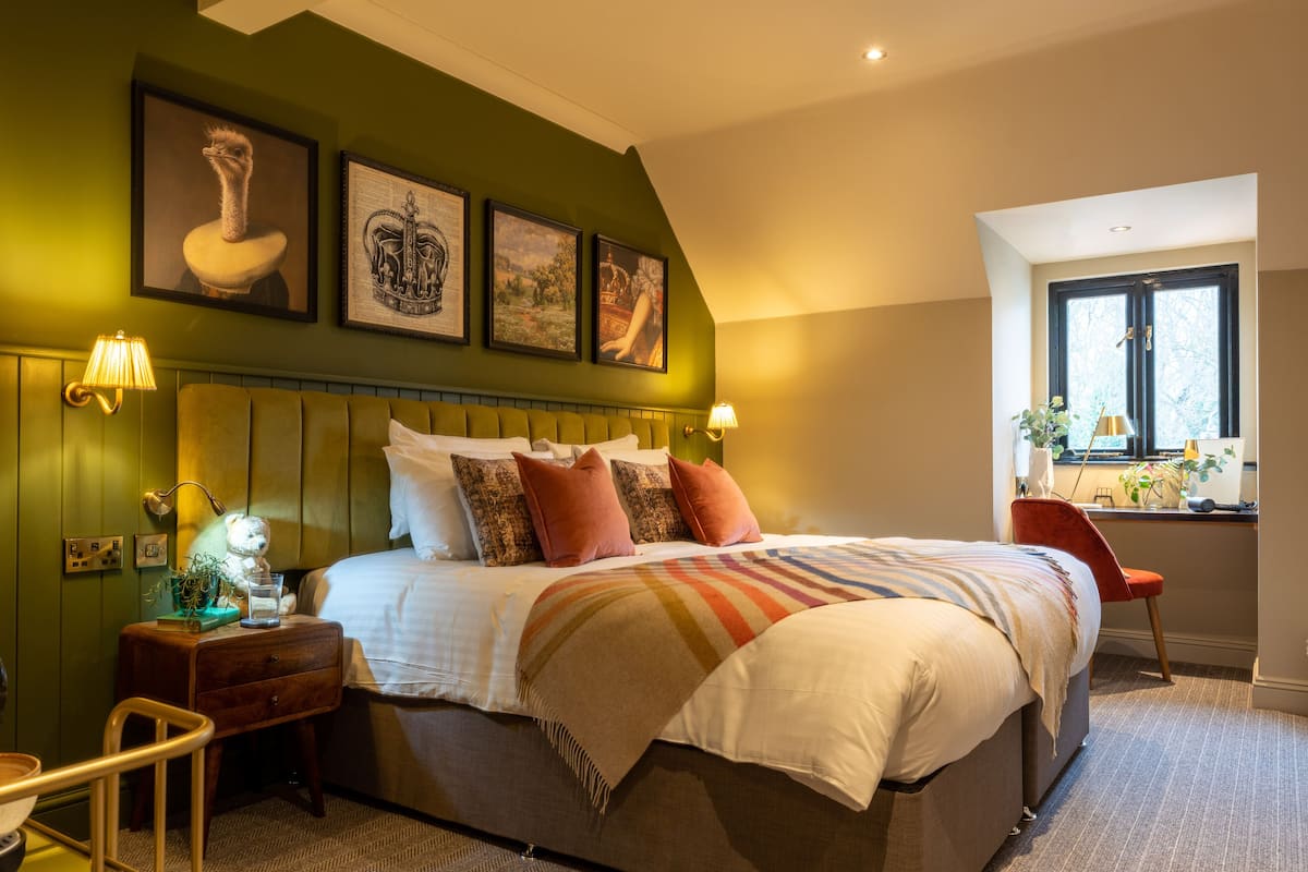 Une chambre bien rangée, avec un lit, des tables de chevet, une chaise et des œuvres d’art accrochées au mur.
