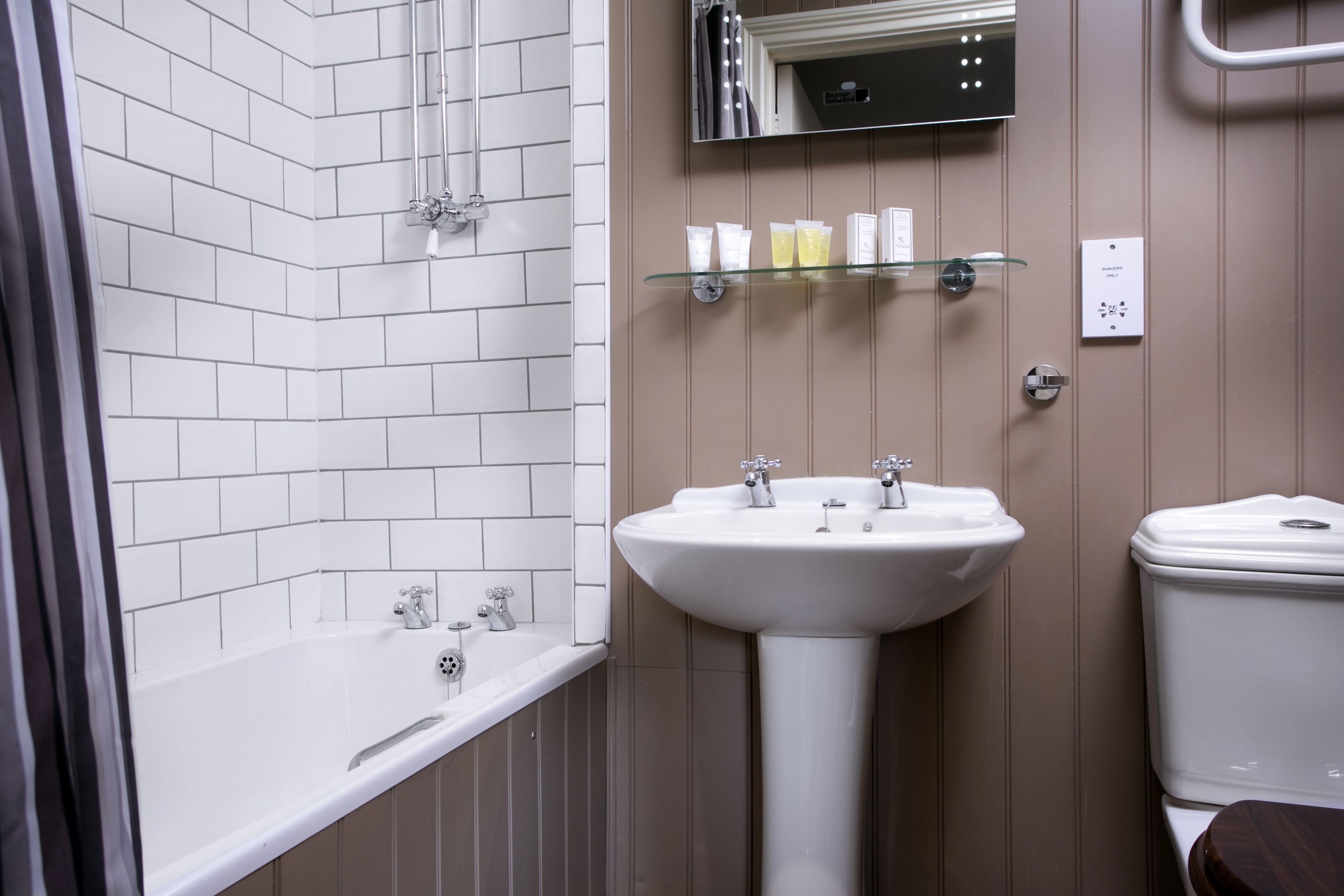 A modern bathroom with a white bathtub, a pedestal sink, and a toilet.