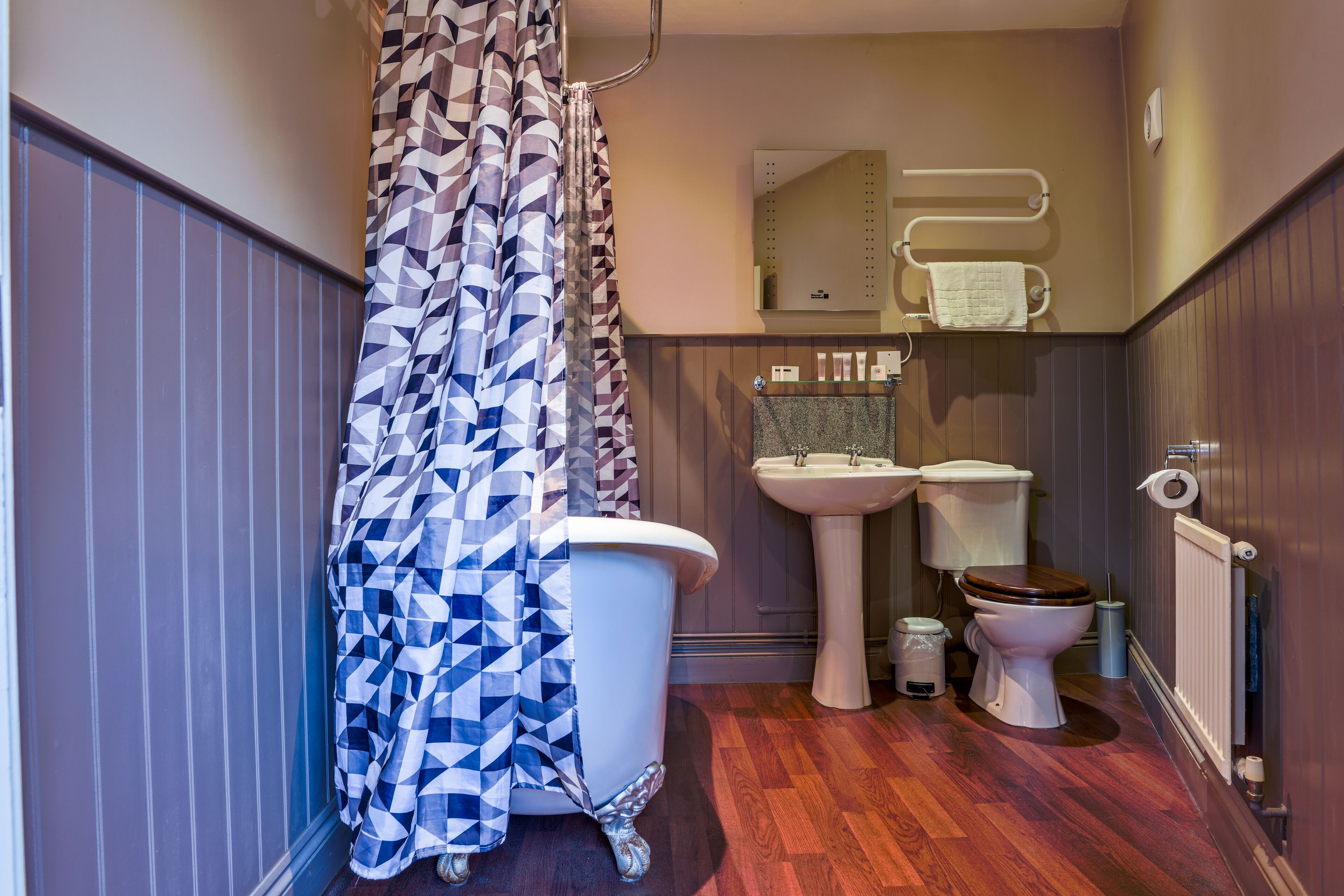 A bathroom with a geometric patterned shower curtain, a white toilet, a sink, and a bidet.