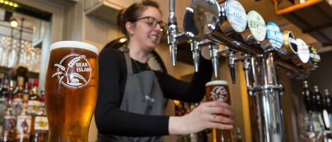 A bartender at a bar with a tap of beer labeled "Bear Island" and a large beer glass.
