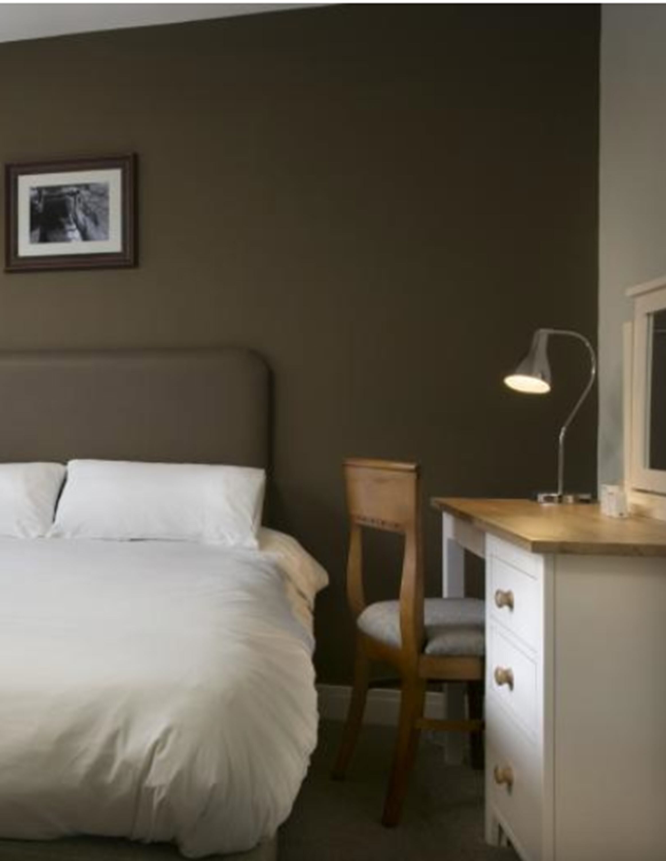 Una camera da letto con un letto, una scrivania, una sedia e una lampada da tavolo.
