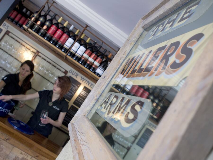 Un celler de vi amb estantes plenes de botelles de vi i un rètol que diu "THE WALLERS ARMS".