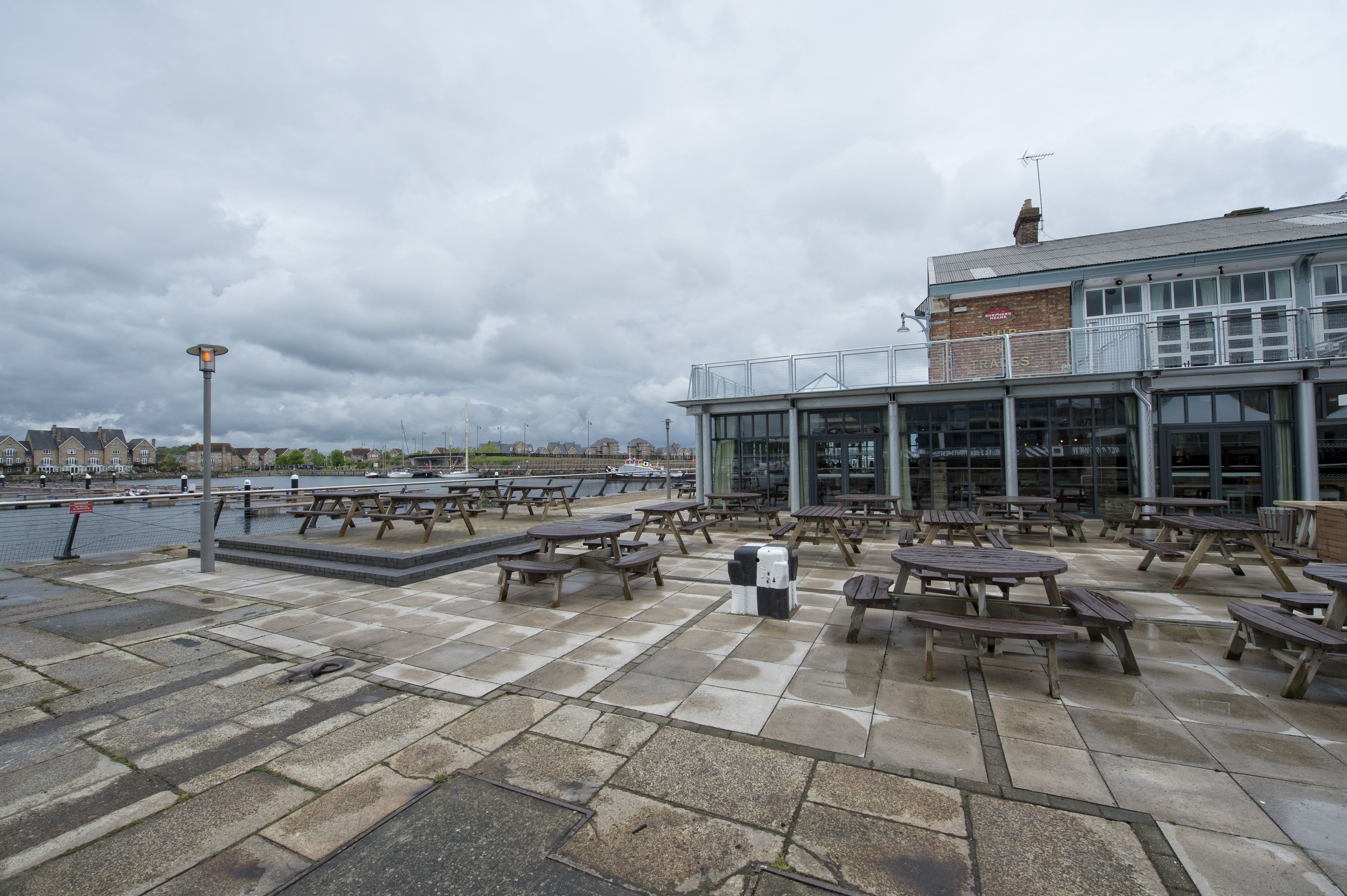 An outdoor seating area with picnic tables and a water body in the background.