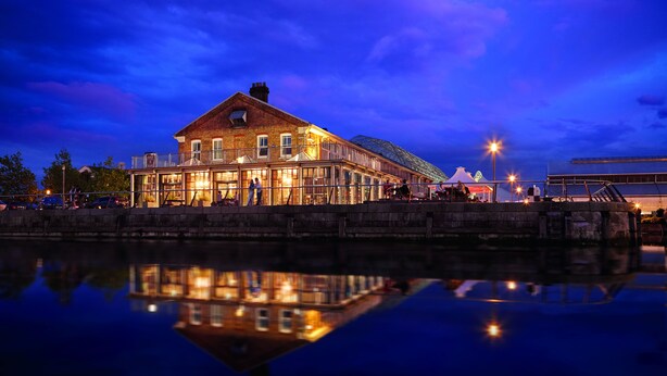 A waterfront building with a glass facade reflecting the lights.
