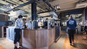 A bar area with a wooden counter, a beer tap, and a menu board.