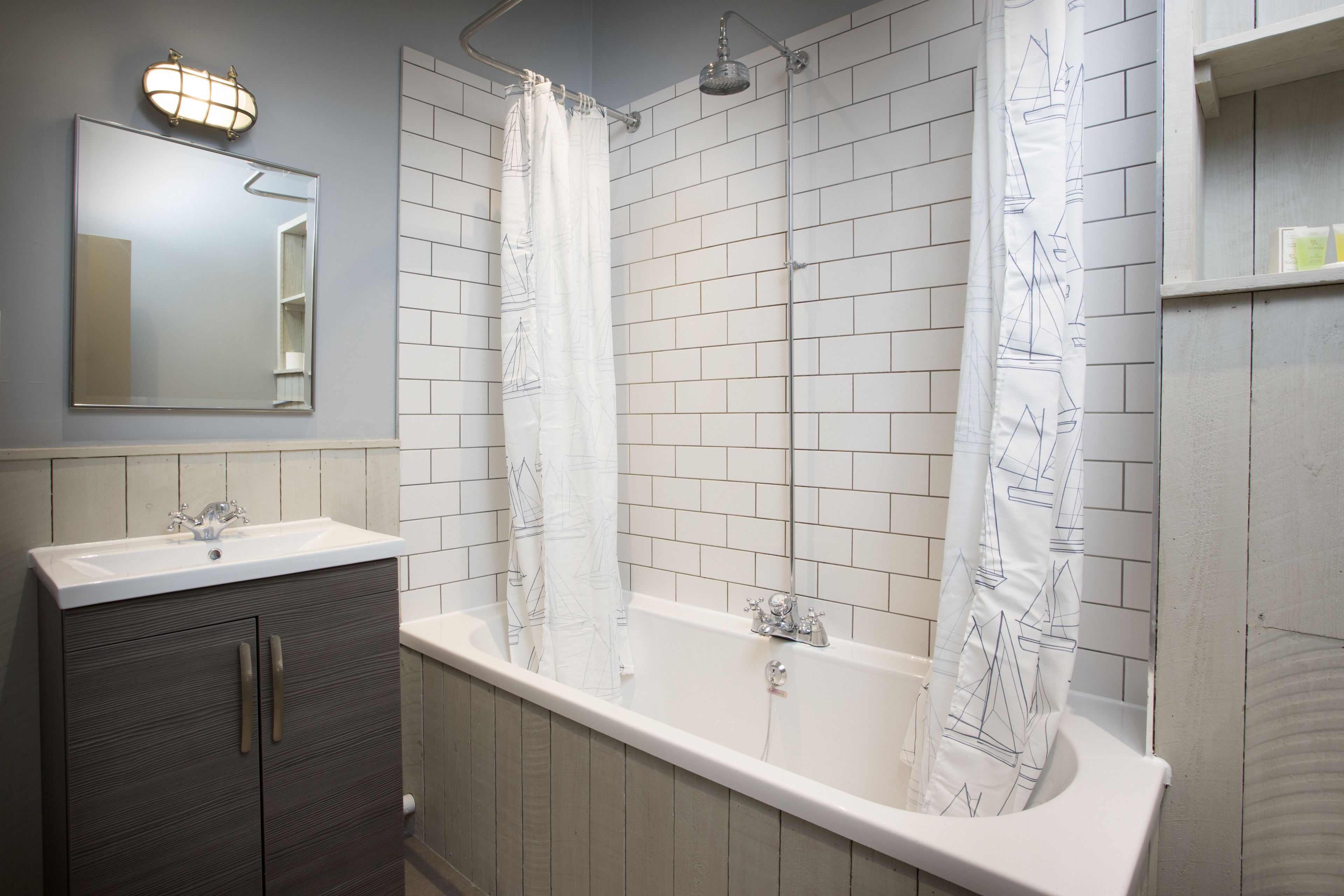 Un baño con bañera, dos lavamanos, un espejo y cortina de ducha.