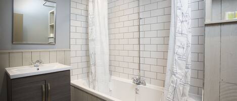 A bathroom with a bathtub, two sinks, a mirror, and a shower curtain.