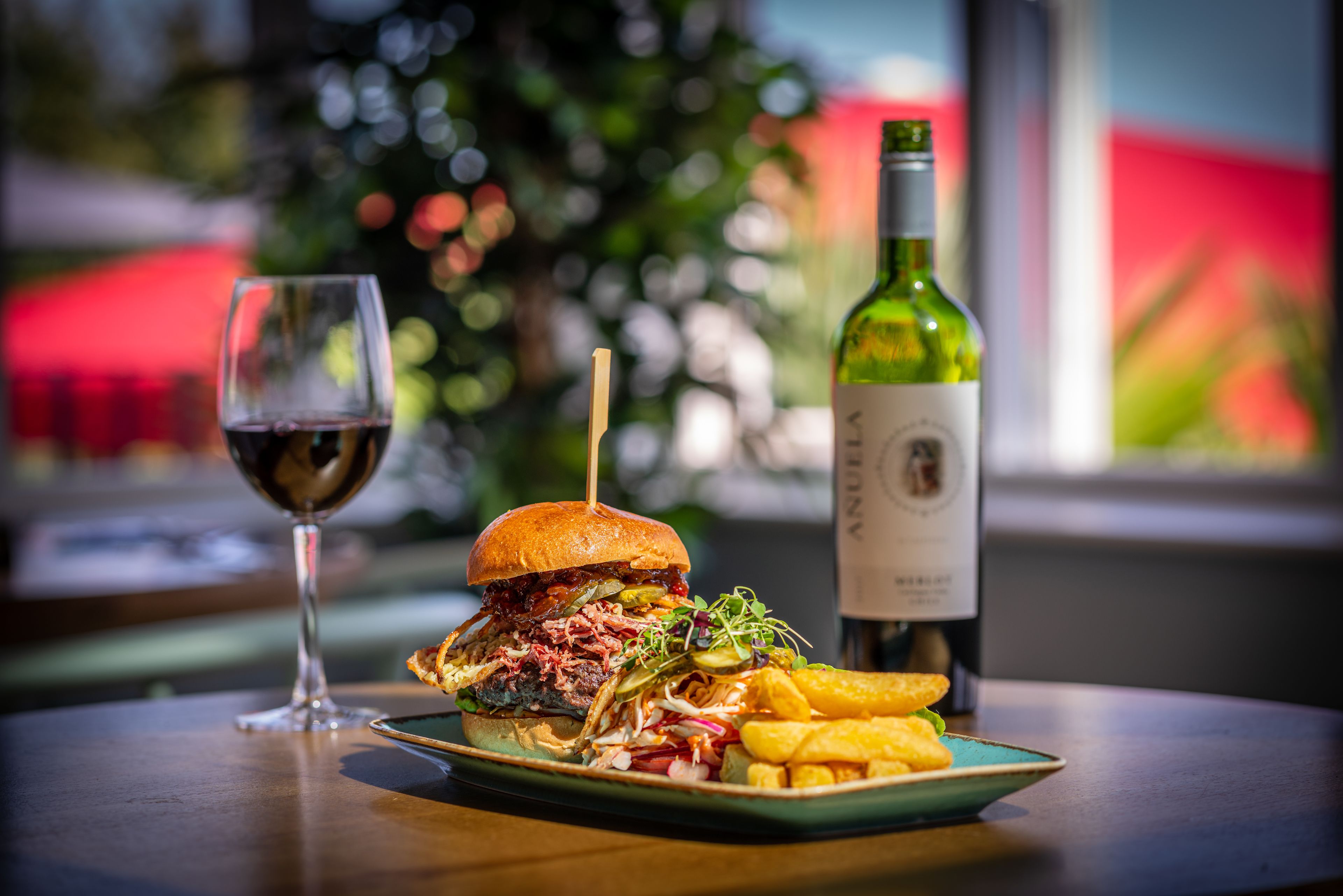 A meal with a burger, fries, and a glass of wine on a table.
