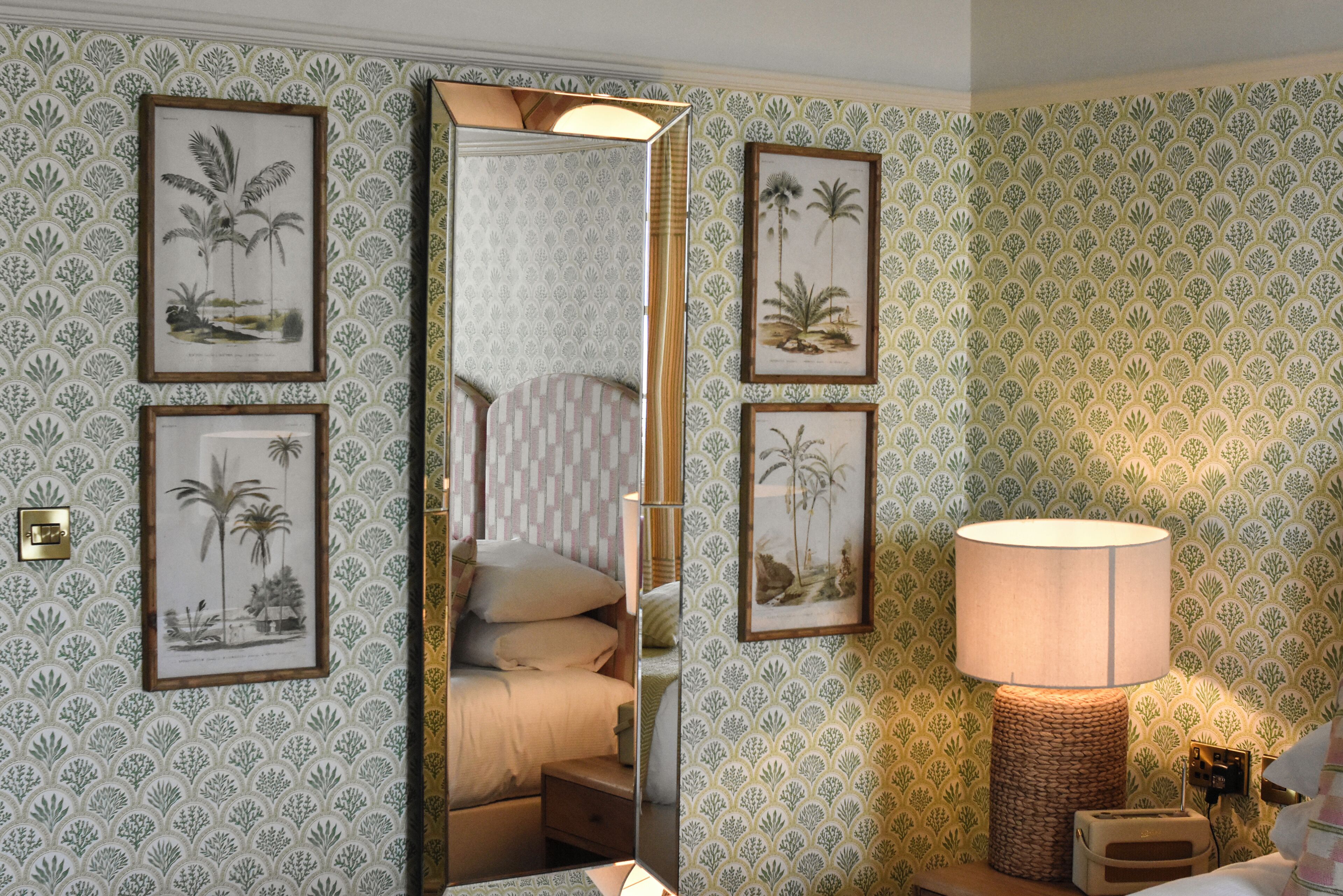 Une chambre d’hôtel avec un lit, une lampe de chevet et des tableaux encadrés au mur.