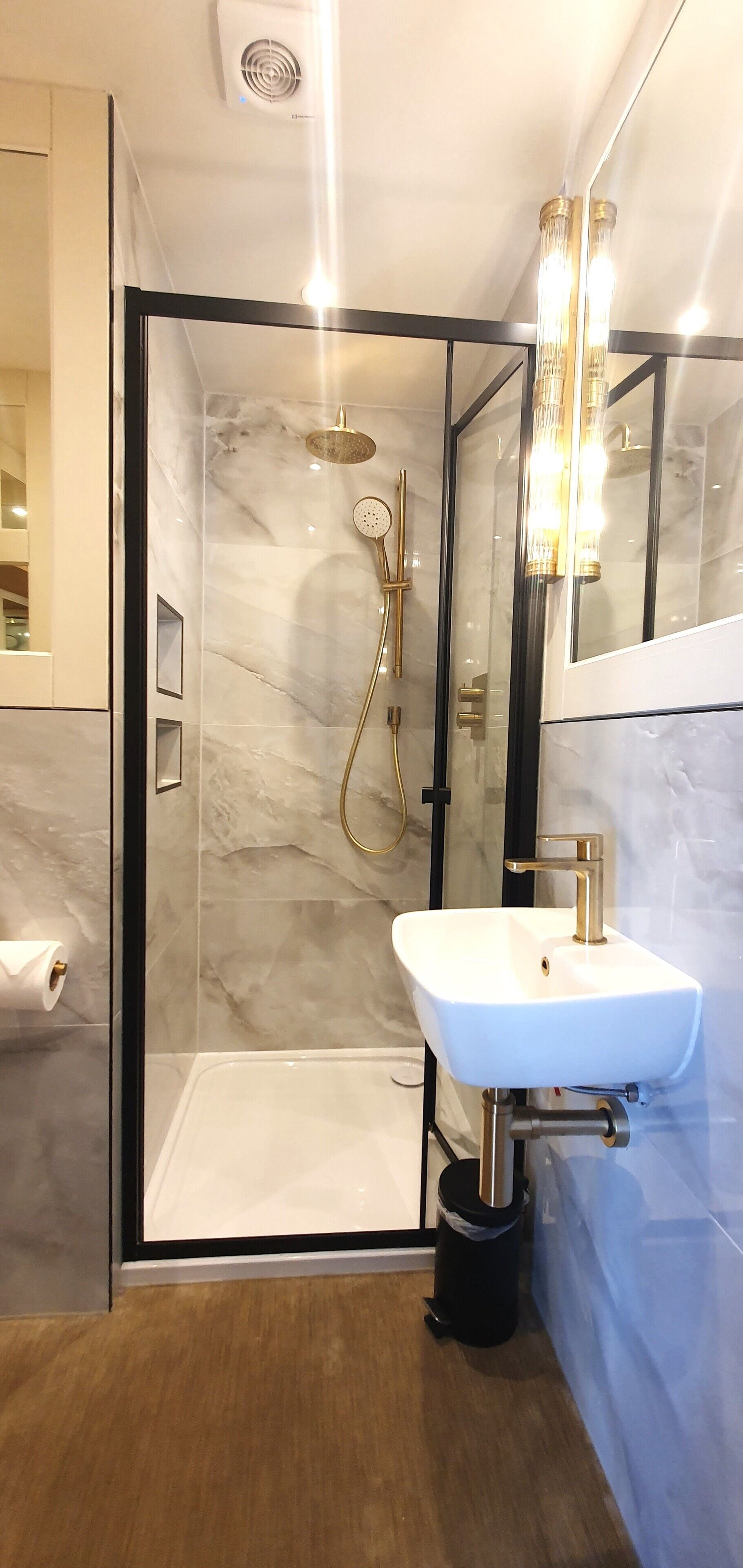 Une salle de bain moderne avec une douche à parois de verre, un lavabo blanc et un miroir.