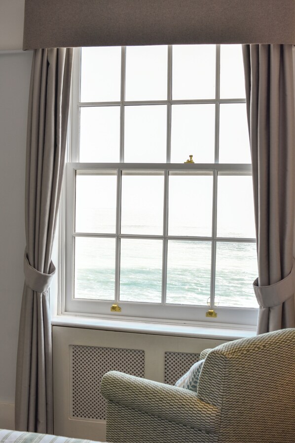 A room with a large window, a radiator, and a patterned chair. - Royal Albion Hotel (Broadstairs)