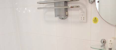 Een badkamer met een wit toilet, een bad, een wastafel en een glazen plank met toiletartikelen.