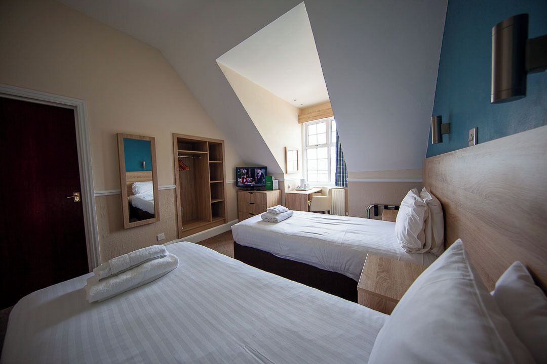 A hotel room with two beds, a desk, a TV, and a wardrobe.