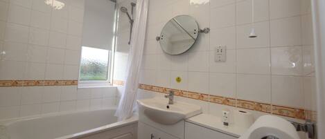 A bathroom with a bathtub, a sink, a mirror, and a toilet.