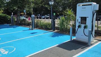 A parking area with electric vehicle charging stations, marked parking spaces, and a clear sky.