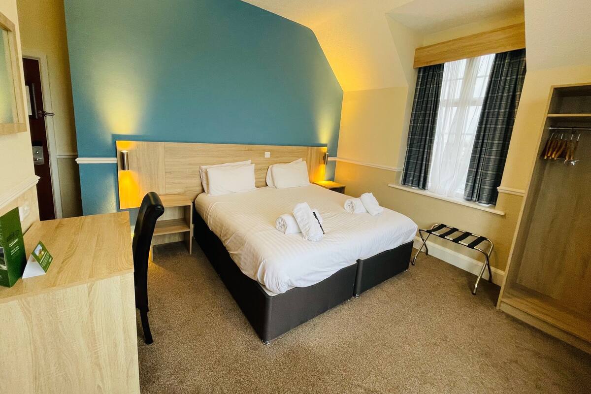 Ein Hotelzimmer mit einem großen Bett, einem Schreibtisch und einem Stuhl.