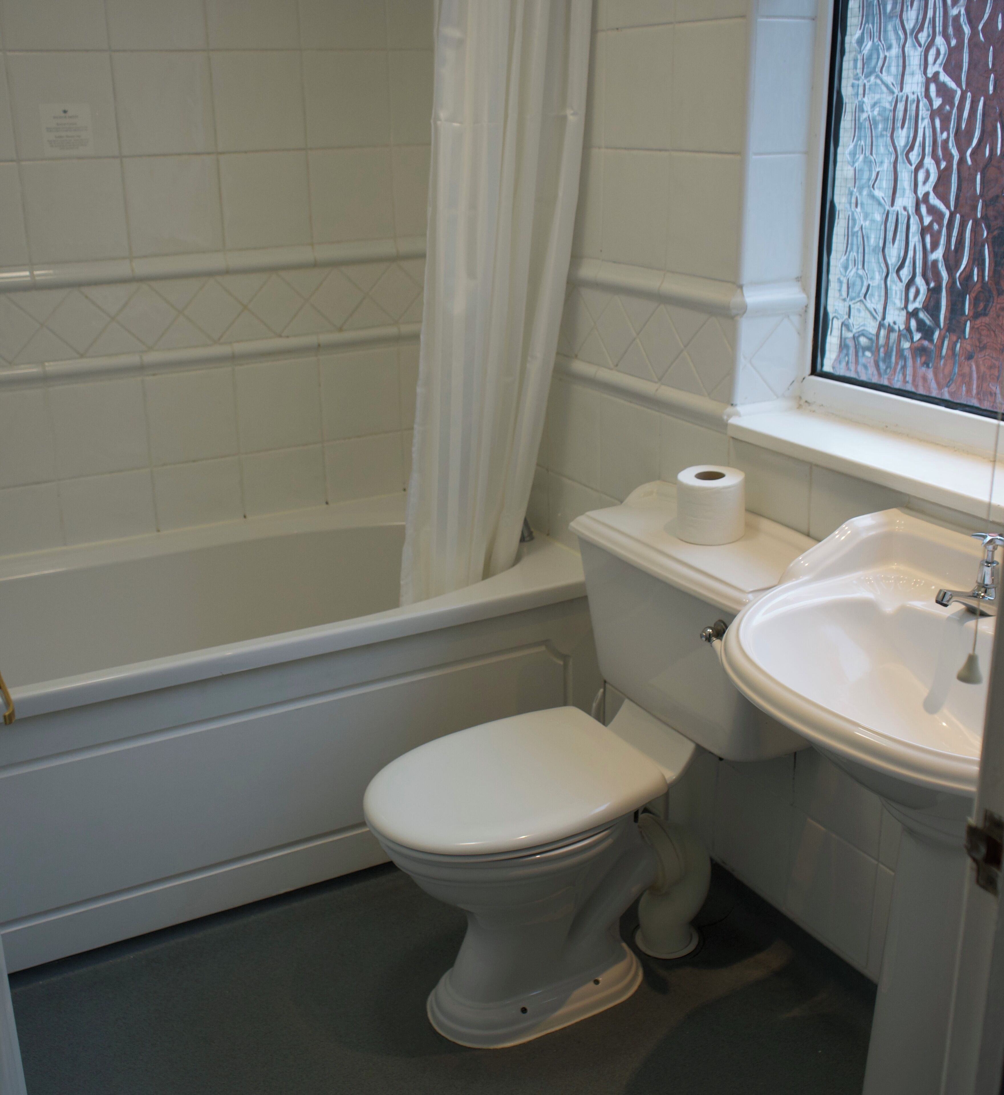 Un baño con una bañera blanca, inodoro y lavabo.