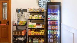 A hotel lobby with a vending machine stocked with snacks and drinks, a self-service beverage dispenser, and a wooden door with a mirror. - B&B Hotel Roma Italia Viminale (Rome)