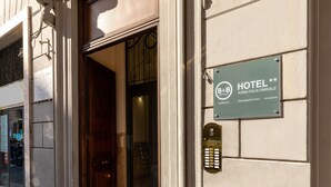 A hotel entrance with a wooden door, a glass door, and a hotel sign on the wall. - B&B Hotel Roma Italia Viminale (Rome)