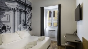 A hotel room with a large bed, a desk, a chair, a television, and a window with curtains. - B&B Hotel Roma Italia Viminale (Rome)
