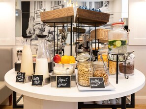 Una mesa de buffet con diversos alimentos y bebidas, que incluye productos lácteos, yogur y opciones saludables.