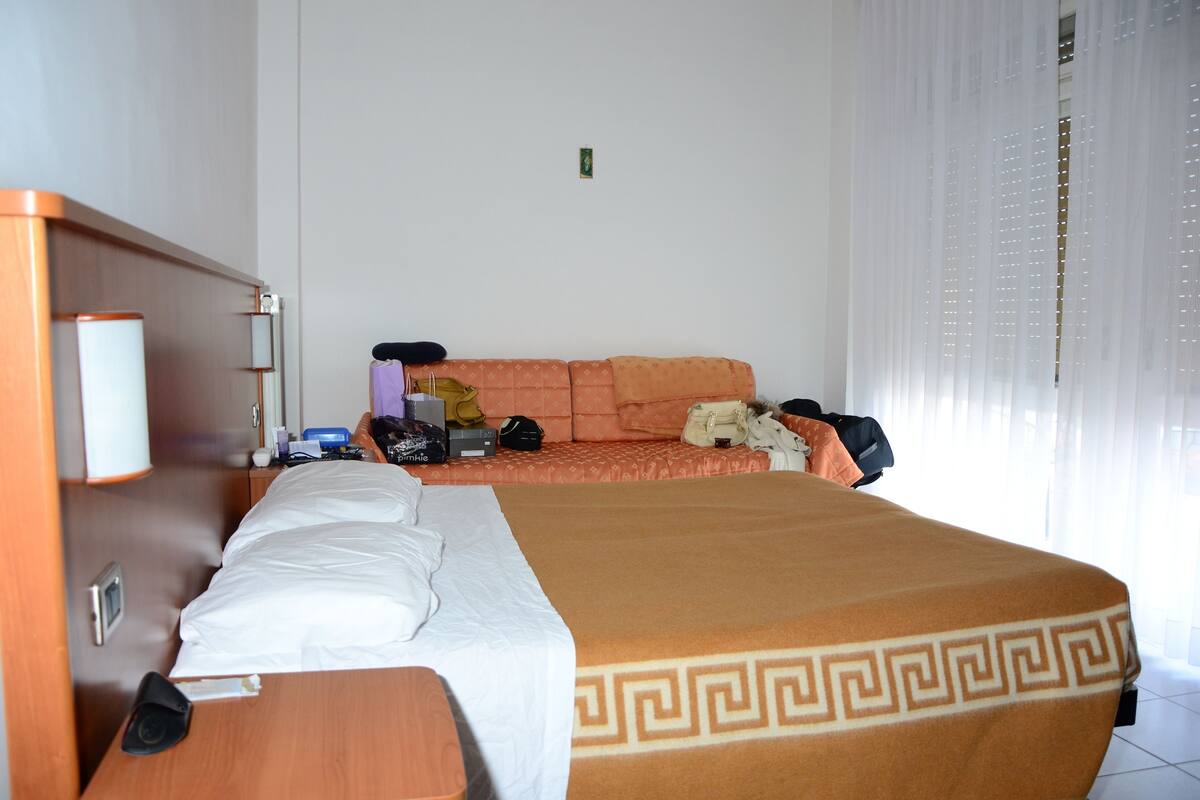 Et hotelværelse med seng, sofa, lille bord og natbord.