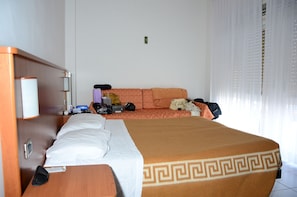 A hotel room with a bed, a sofa, a small table, and a nightstand.