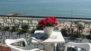 A balcony with a table and chairs overlooking a coastal view.