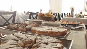 A buffet table with various baked goods, including pastries and bread, arranged on trays and plates.