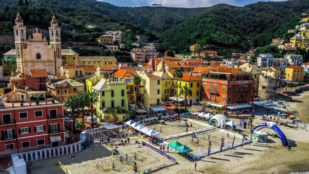 A coastal town with a prominent church, colorful buildings, and a sandy beach area.