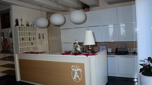 A reception desk with a logo, a white cabinet with a printer, and a hanging spherical light fixture.