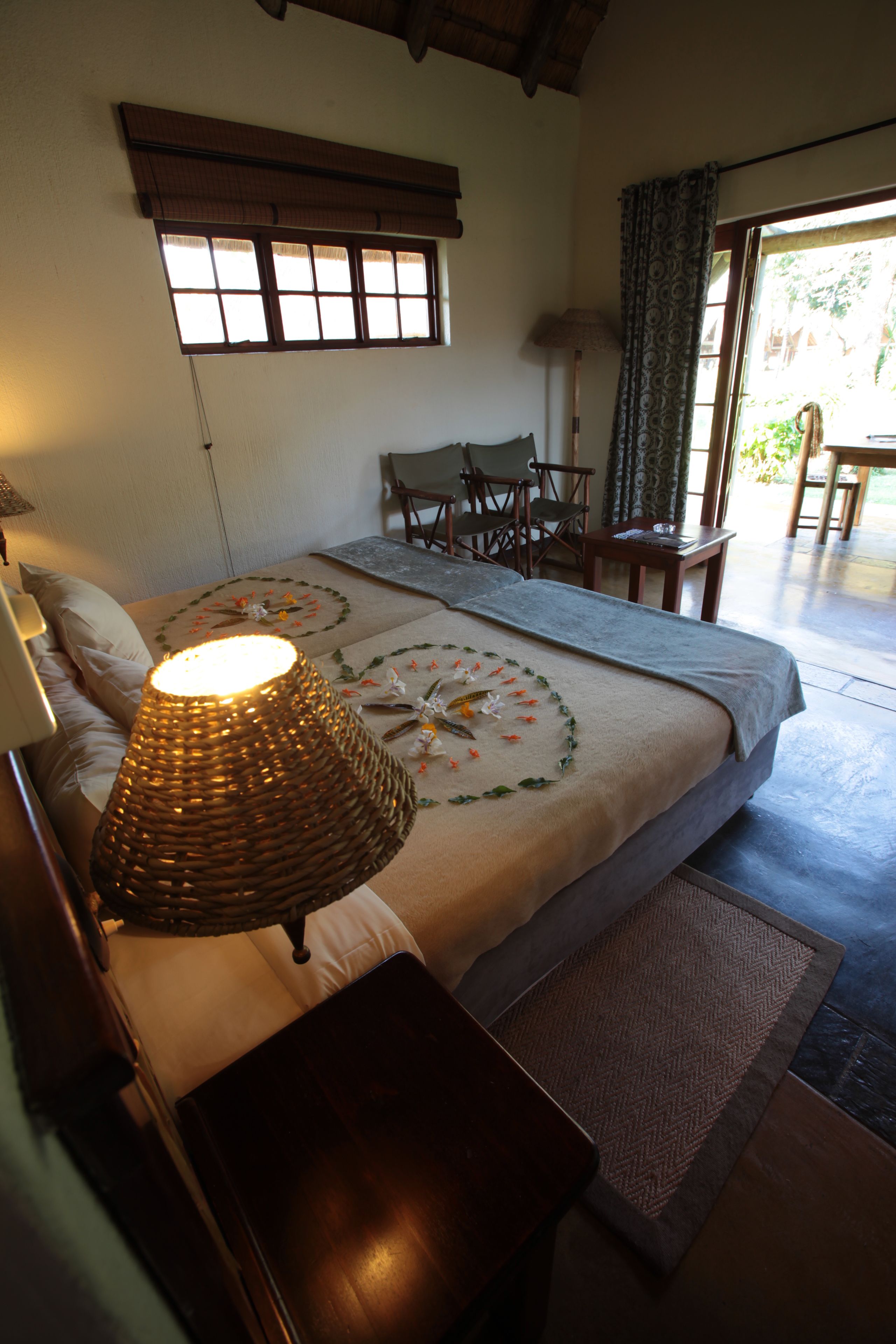 Un dormitorio con cama, lámpara de noche, una silla y una mesa.