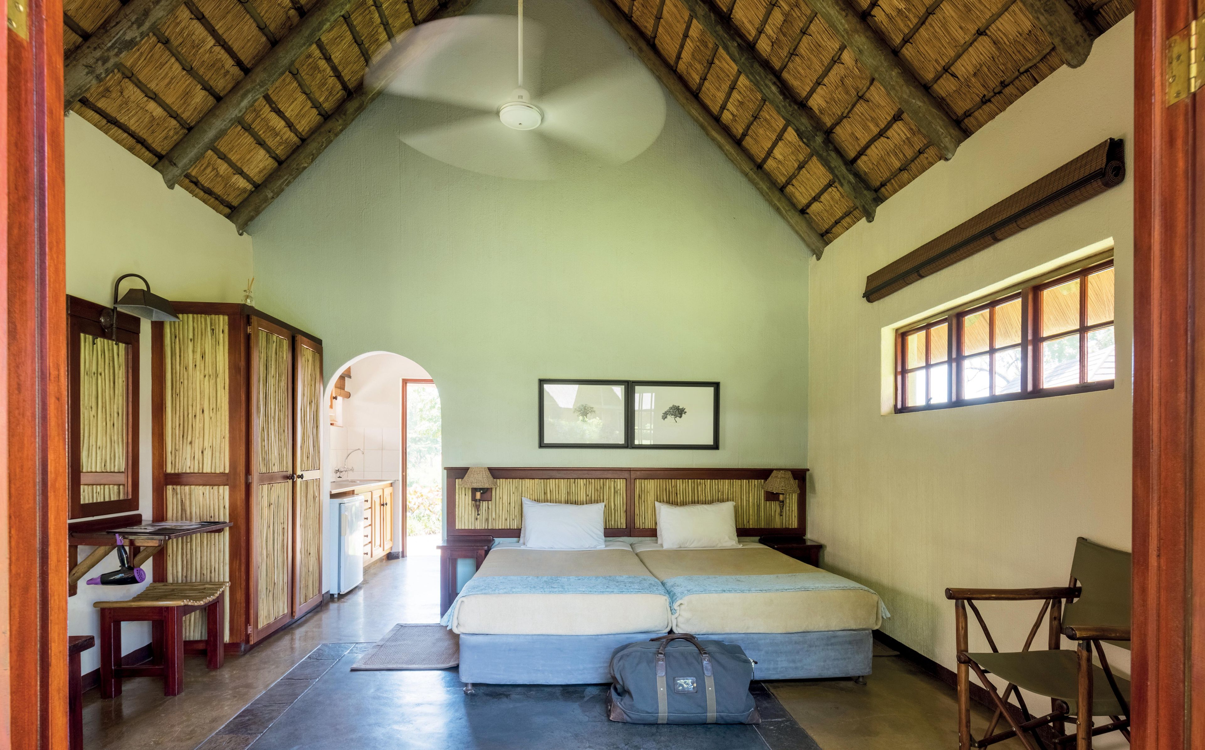 Una habitación con techo alto, una cama, un escritorio y una silla.