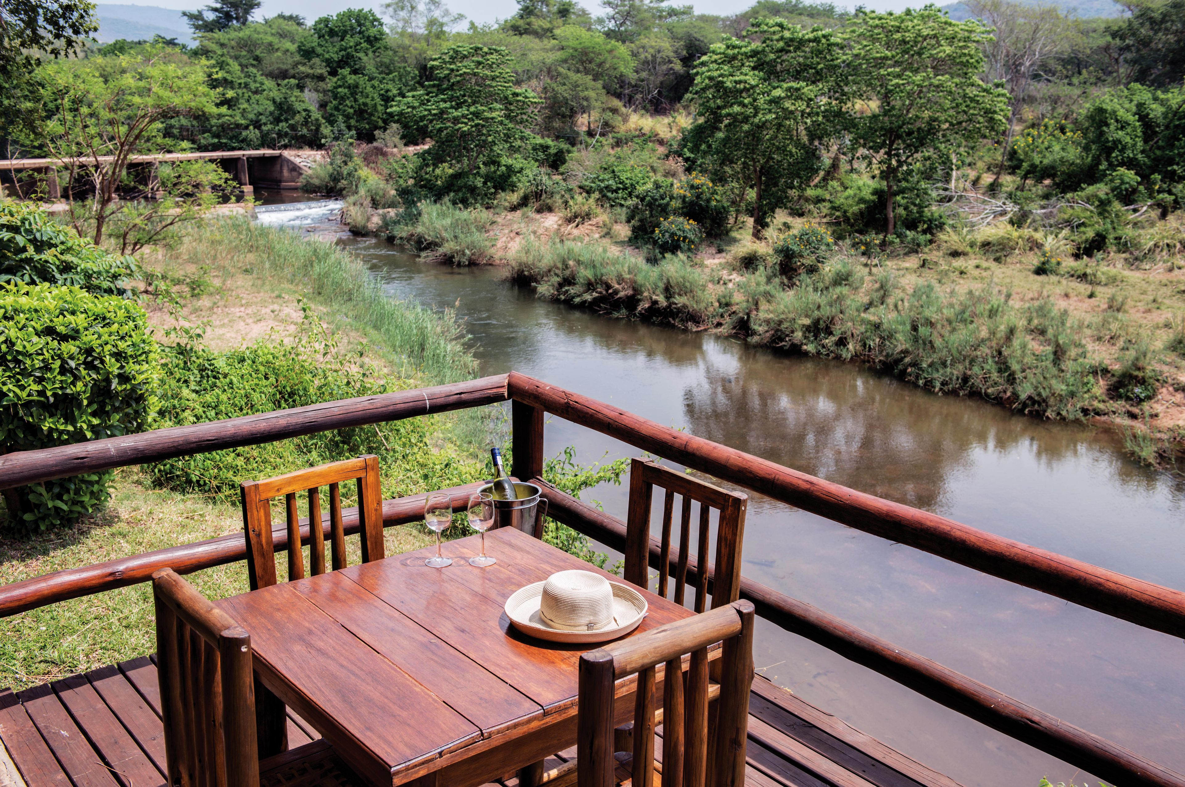 A wooden deck with a table and chairs overlooking a river.