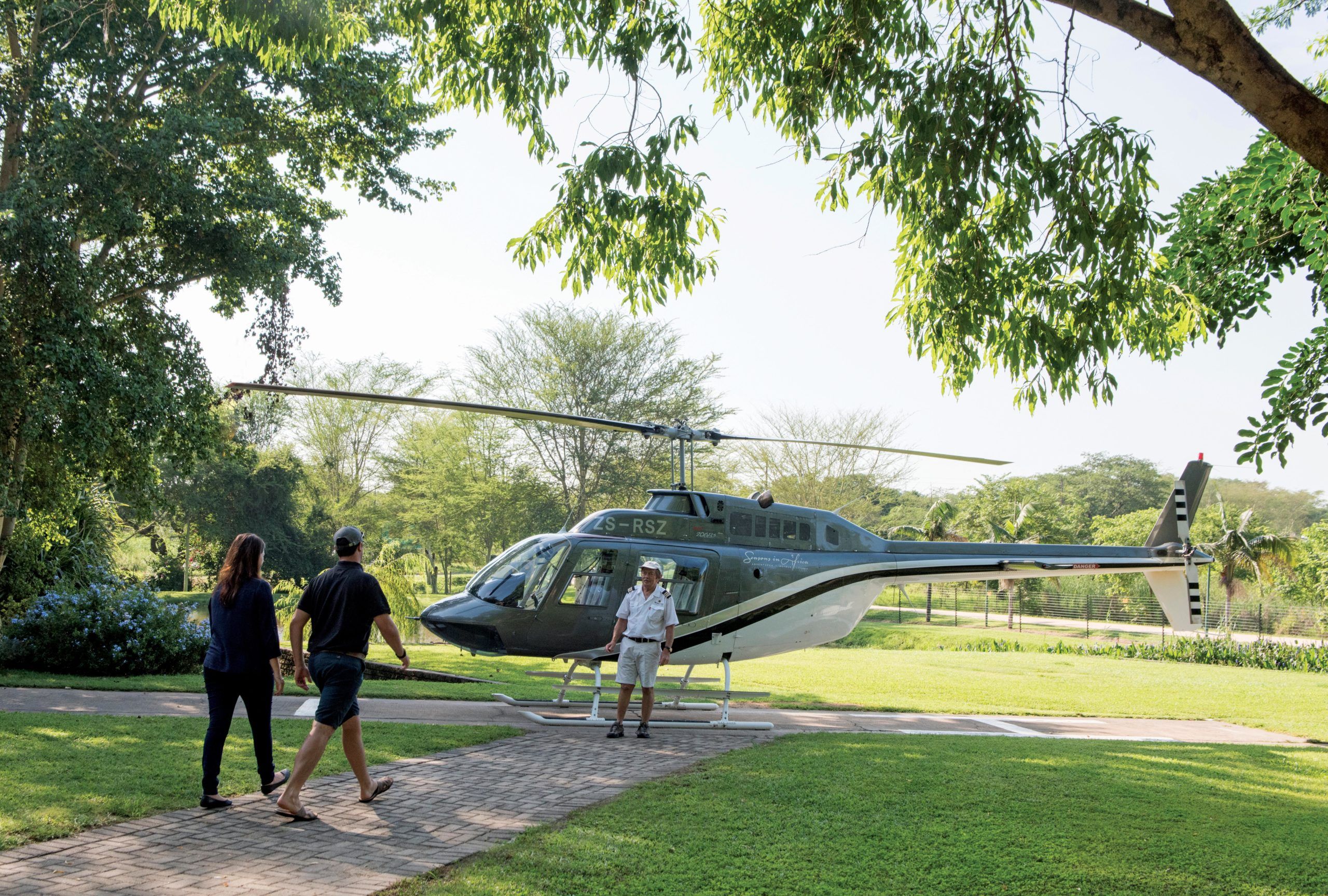 A helicopter parked in a grassy area with trees in the background.