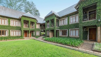 A building with multiple balconies, large windows, and a well-maintained lawn.