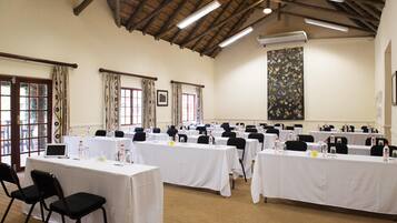 A conference room with multiple tables, chairs, and a large abstract painting on the wall.