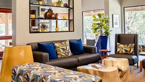 A modern living room with a high ceiling, exposed beams, and a large window. - Hippo Hollow Country Estate (Mbombela)