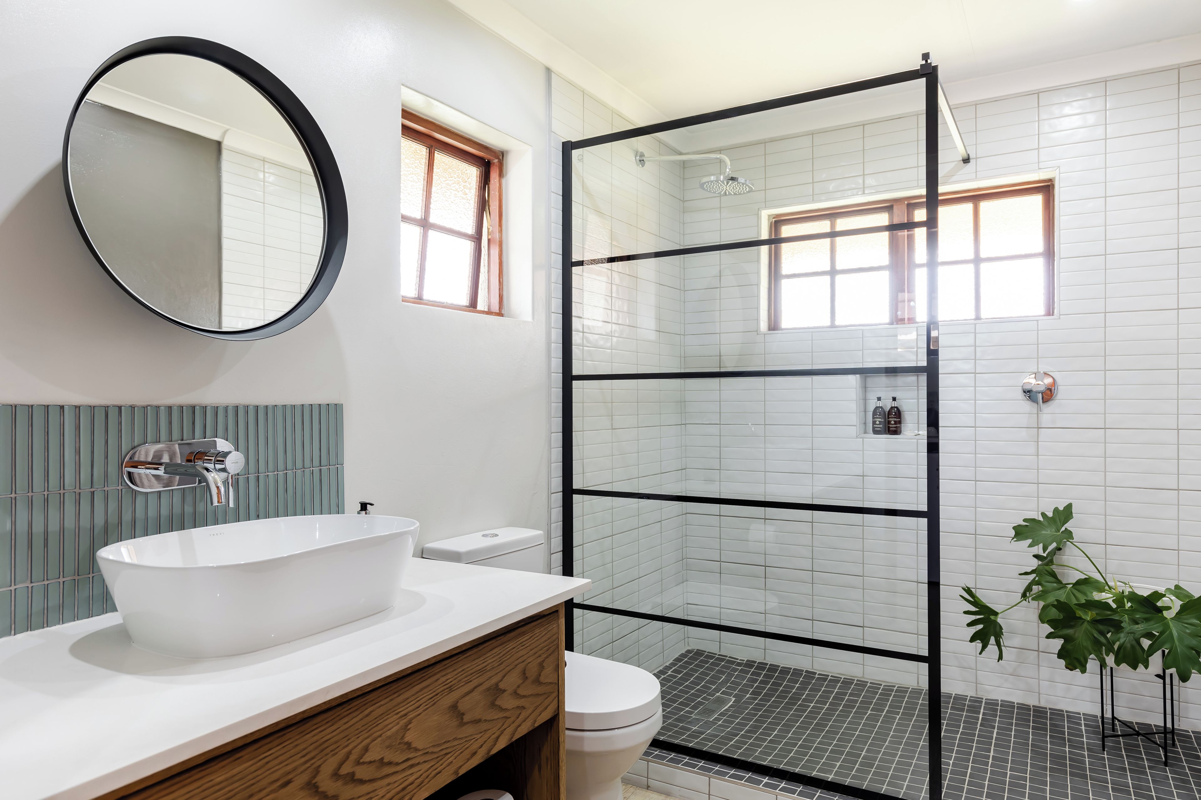 A bathroom with a large oval sink, a glass shower enclosure, and a mirror on the wall.
