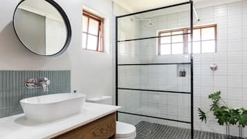 A bathroom with a large oval sink, a glass shower enclosure, and a mirror on the wall.