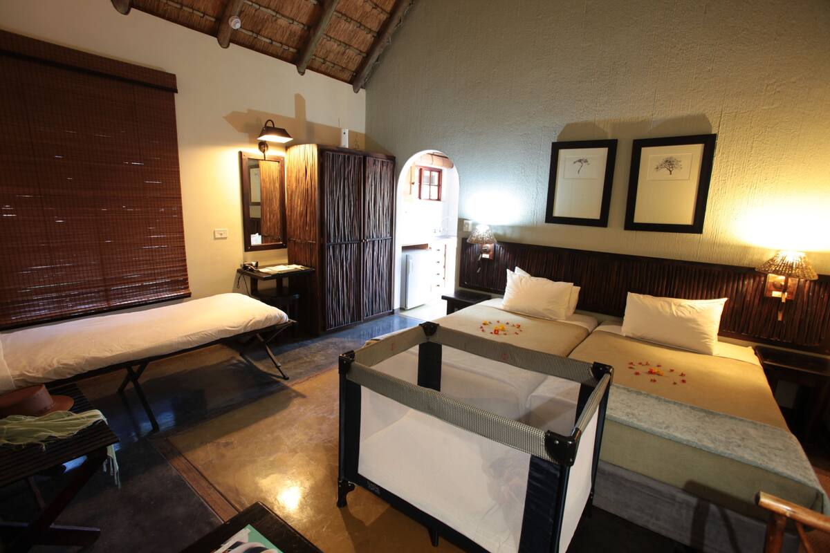 Una habitación de hotel con una cama, un banco, una mesita y un espejo.