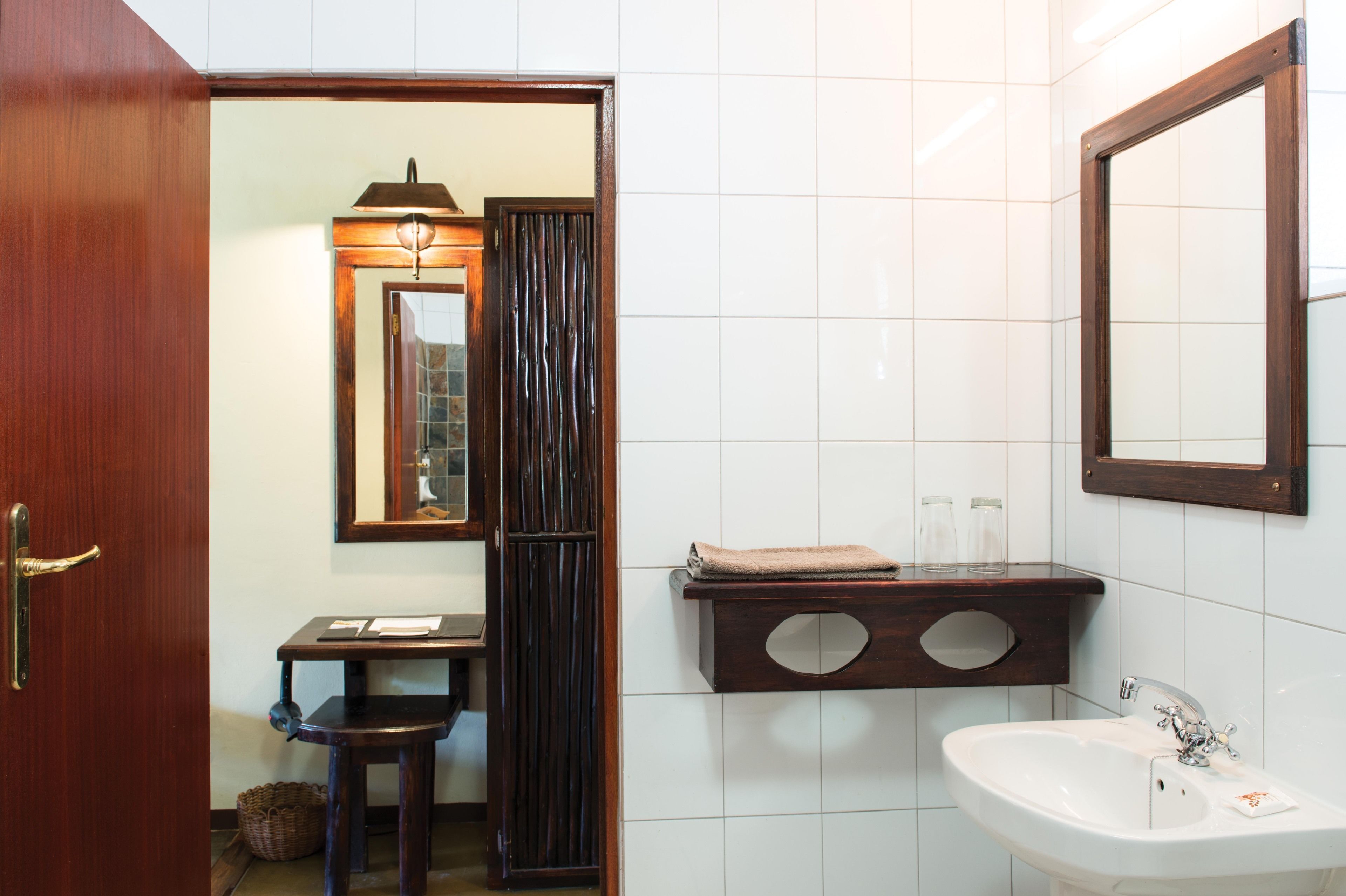 A bathroom with a wooden door, a sink with a mirror, and a towel rack.