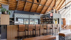 A bar area with wooden slats, bar stools, and a counter with bottles. - Hippo Hollow Country Estate (Mbombela)
