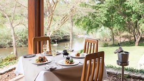A dining table set for two with plates of food, glasses, and cutlery. - Hippo Hollow Country Estate (Mbombela)