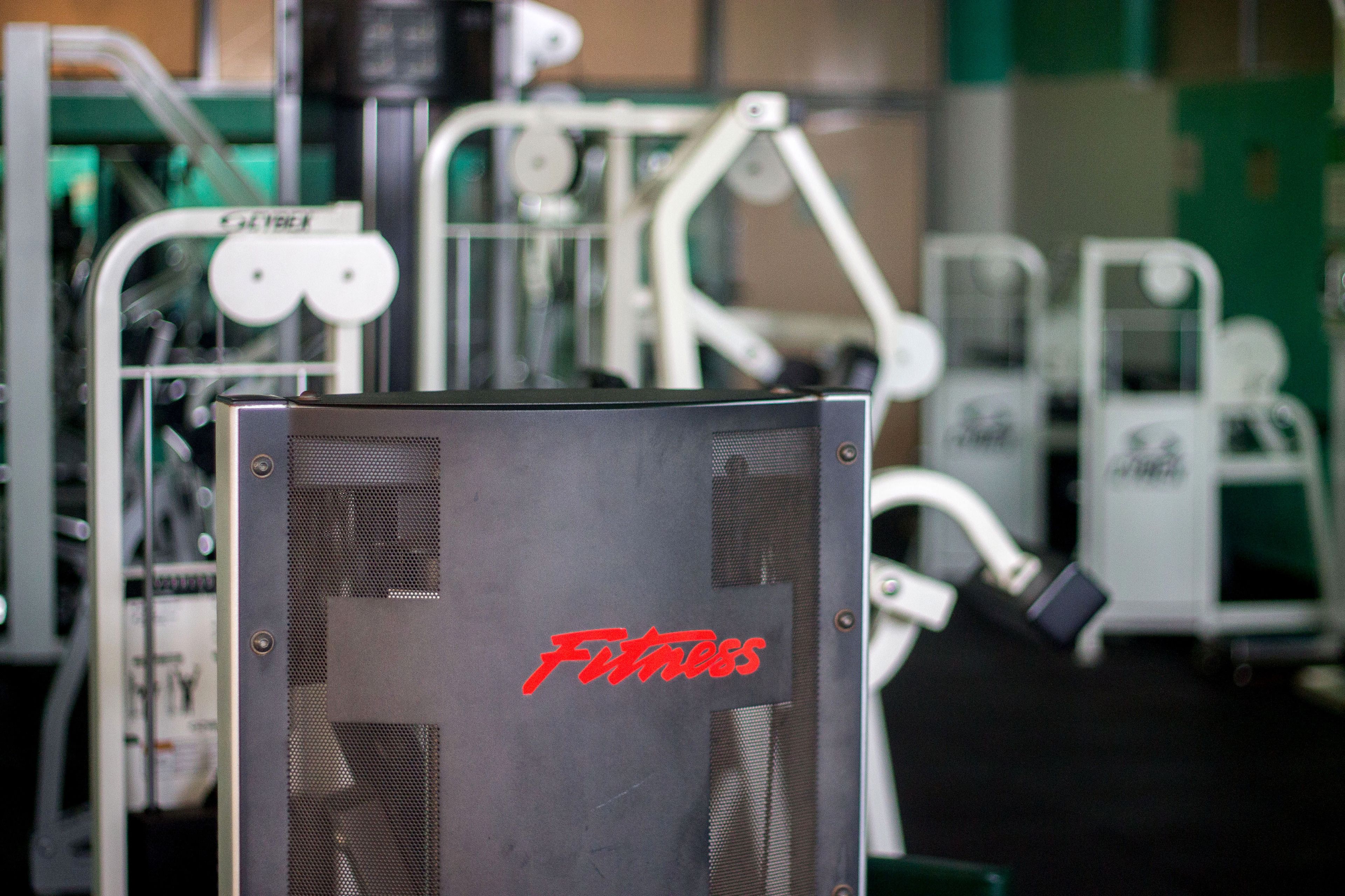 A gym with various exercise equipment, including a visible weight stack labeled "FITTNESS".